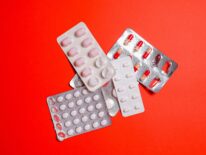 Here's an alt tag for the image: Pill blister packs on red background.