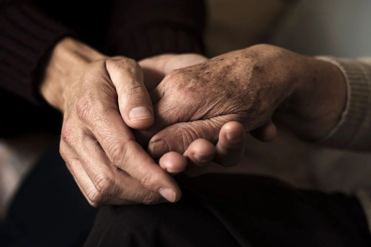 Two hands clasped together, showing support during grief or loss