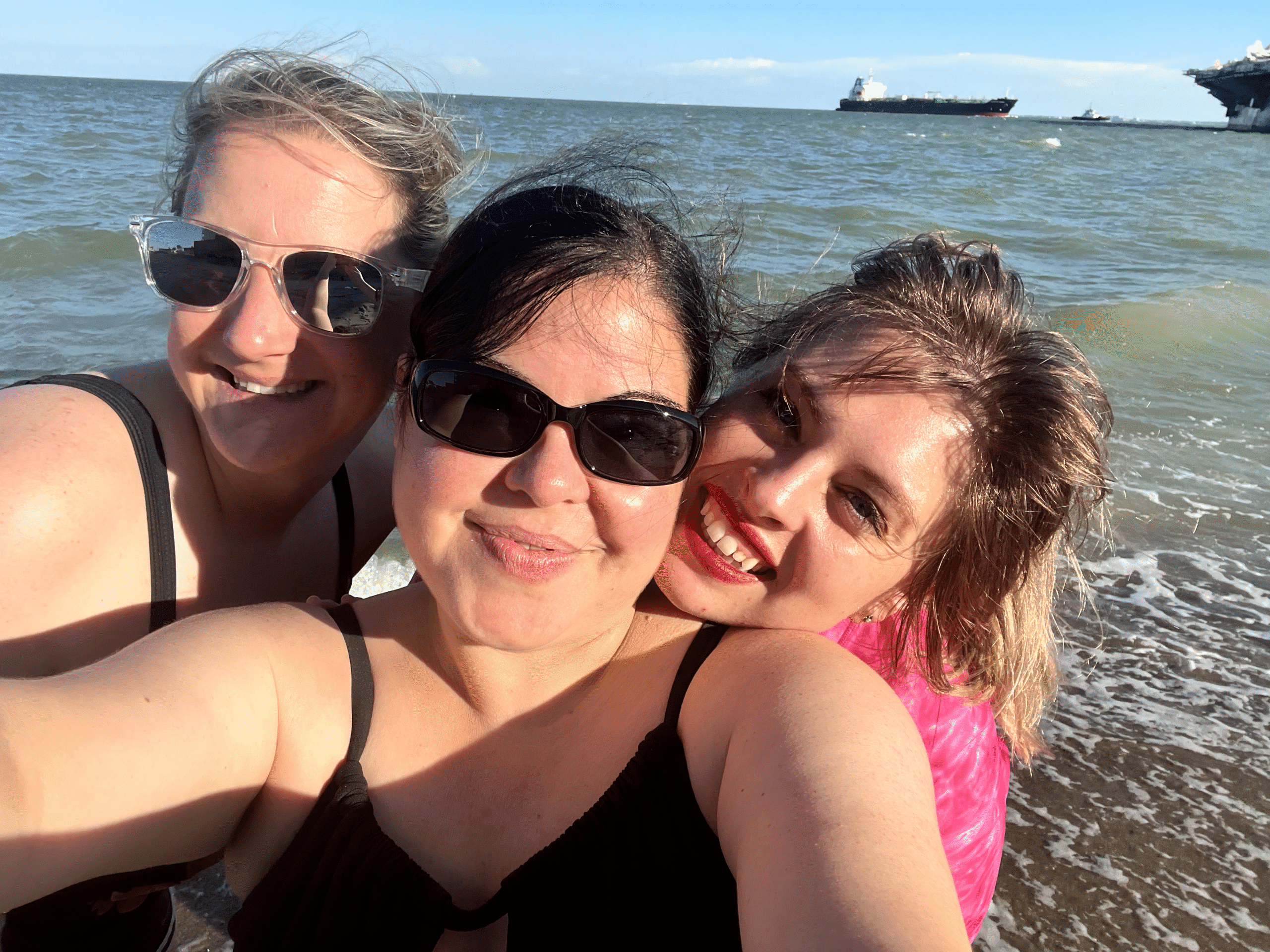 IMG_8635.heic Three women smiling on a sunny beach.