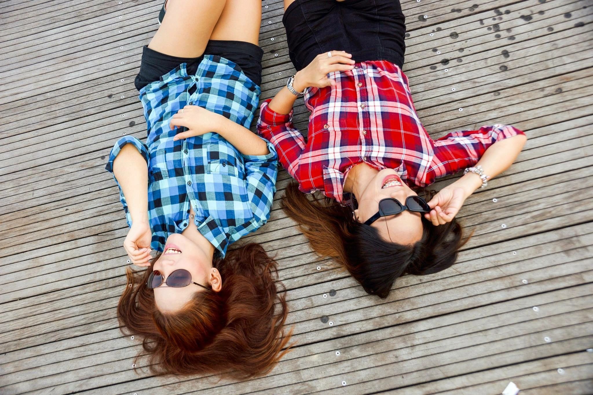 qtq80-GK8CMM Two women in plaid shirts lying down.