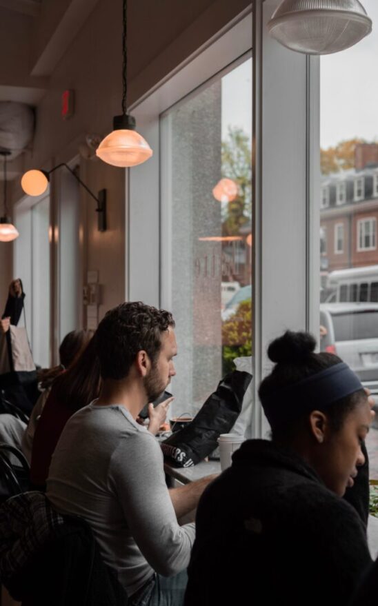 Two people sitting by window, coffee shop.