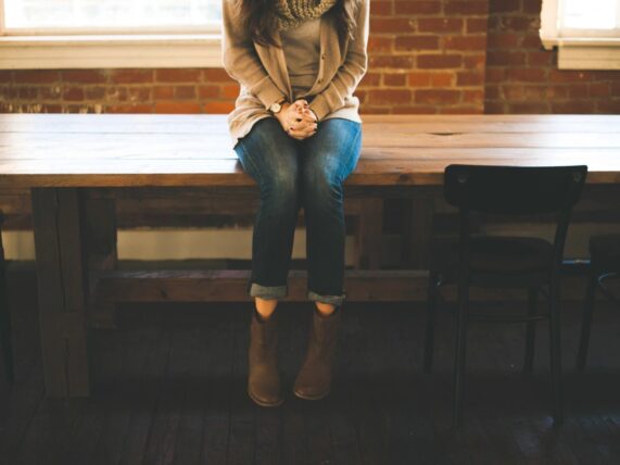 Woman sitting at wooden table, brown boots.