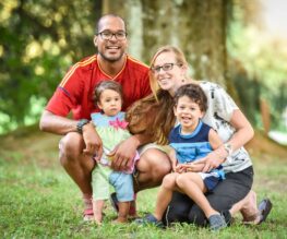 Happy family with two young children in park.